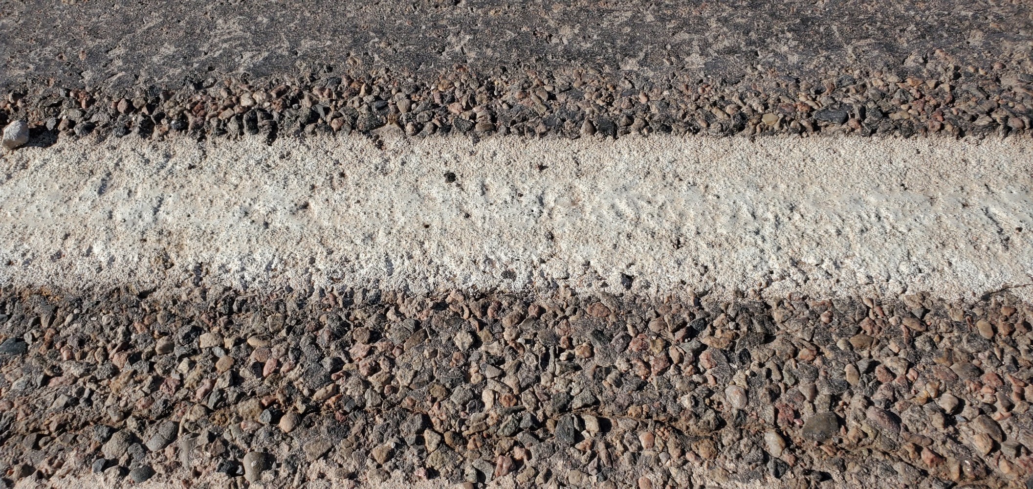 It's hard to see, but the white line is painted in a depression that is prone to catching bicycle wheels. When I first encountered this, I thought, "What fresh hell have the road engineers come up with this time?" I suppose it is to reduce wear on the paint, but it is a pain.